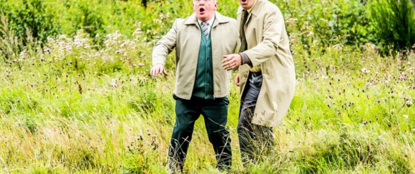 a man standing next to a green field