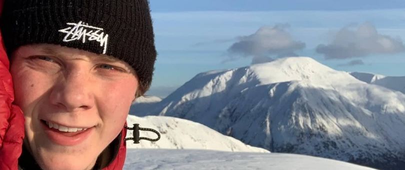 a person wearing a hat and a snow covered mountain