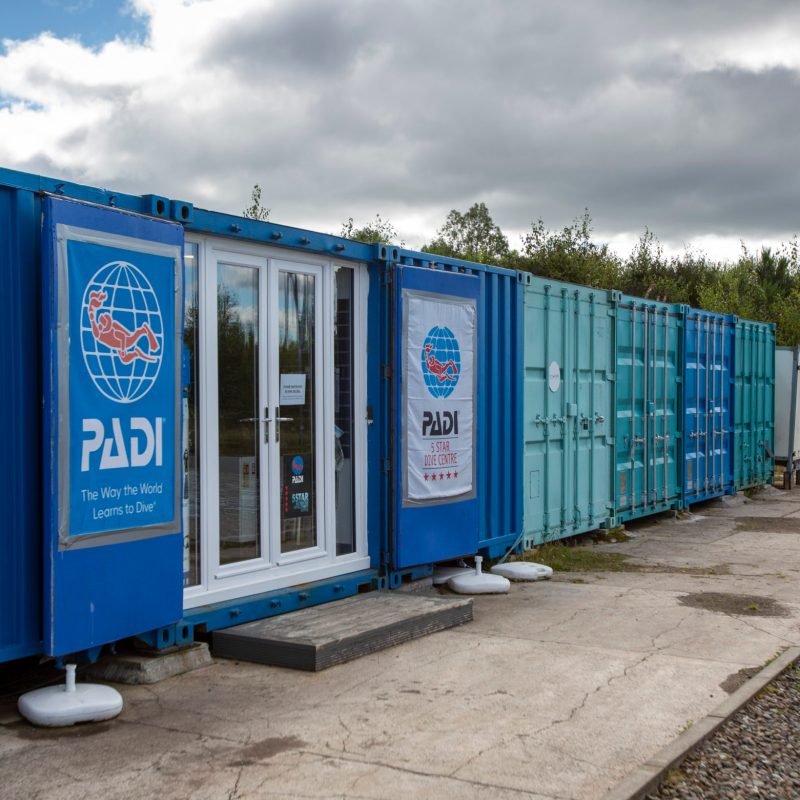 a blue and white train sitting on the side of the road