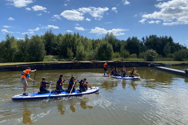 Groups paddleboarding on a lake under a sunny sky.