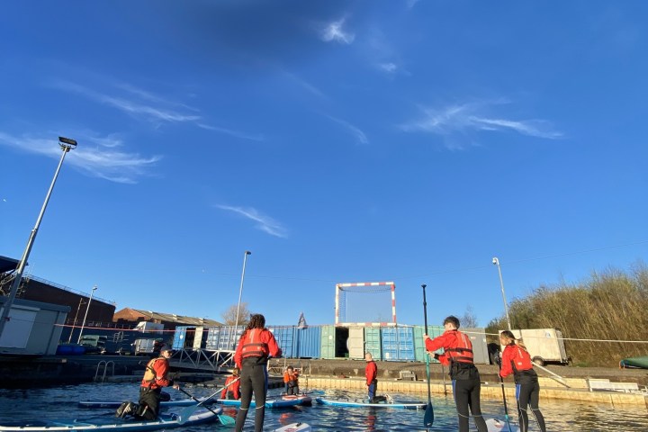 Group paddleboarding on a sunny day with blue sky.