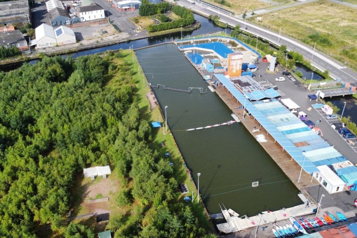 Aerial view of a wakeboarding park with ramps and trees nearby.