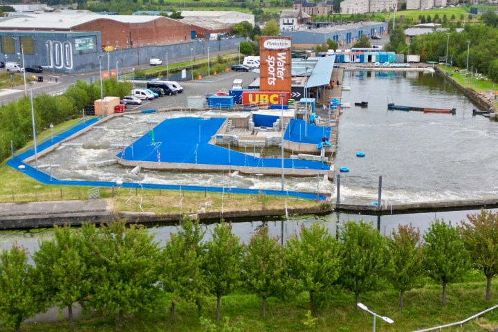 Aerial view of a watersports facility with a blue course and adjacent canal.