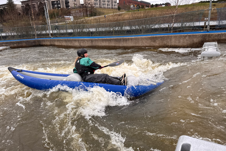 Person kayaking on rapid waters at an outdoor course.