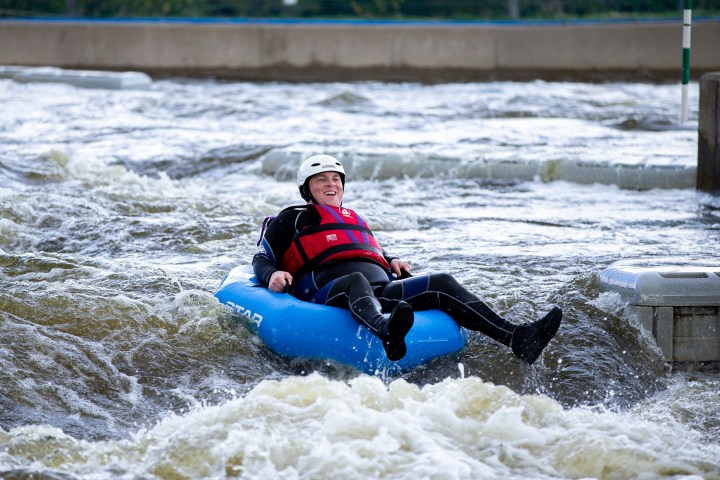 Person in a wetsuit and helmet tubing on whitewater rapids.