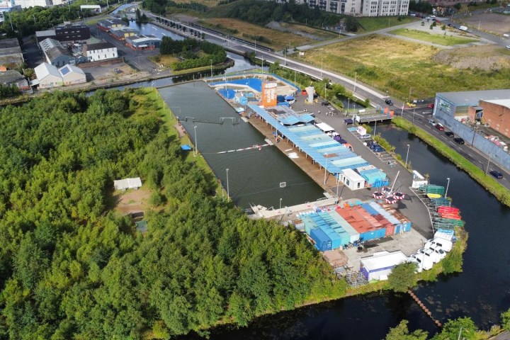 Aerial view of an industrial site with warehouses, green area, and adjacent waterways.