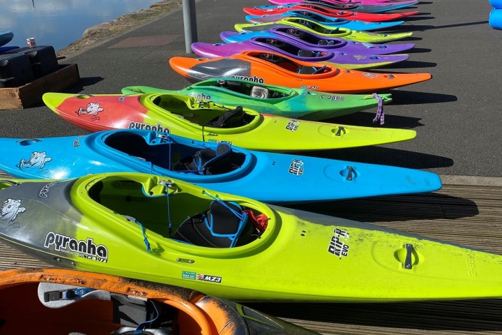 Colorful kayaks lined up by a waterfront on a sunny day.