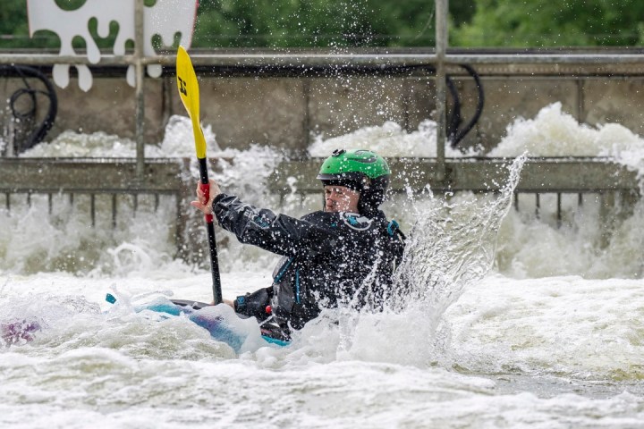Person kayaking through turbulent water with a yellow paddle.
