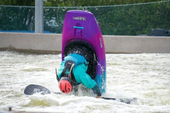 Person doing a kayak flip maneuver in whitewater.