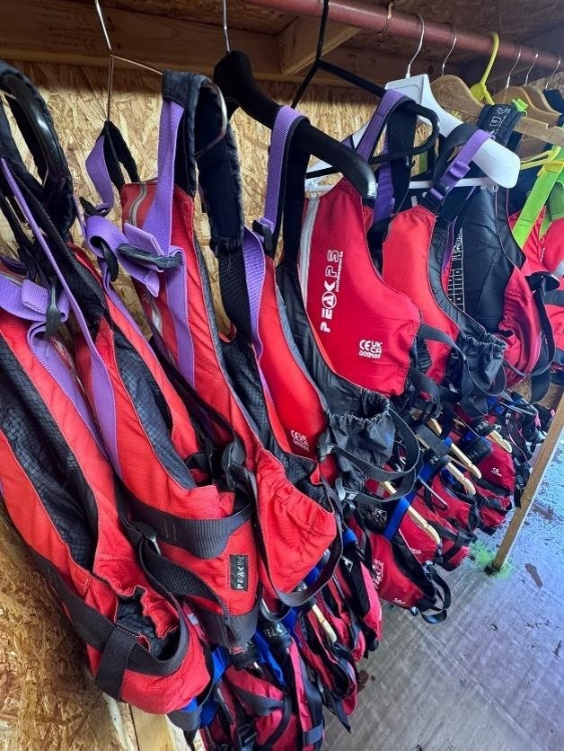 Red and purple life jackets hanging on a wooden rack.