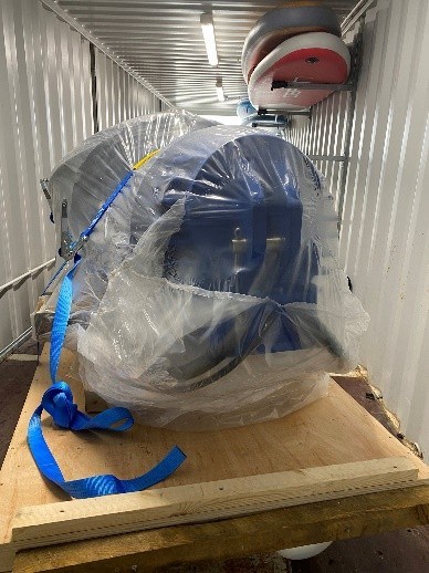 Covered machinery inside a shipping container on a wooden pallet.